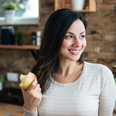 Woman eating an apple in her kitchen.
