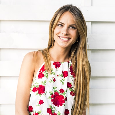 Woman with flower-patterned top and long hair smiling with perfect teeth.
