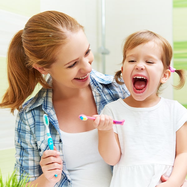 Kid brushing teeth with mom after learning about children's dentistry