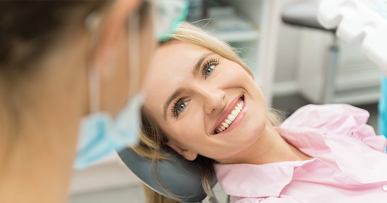 A woman smiling while sitting in dental chair.